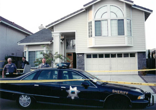 house with police car and yellow tape in front