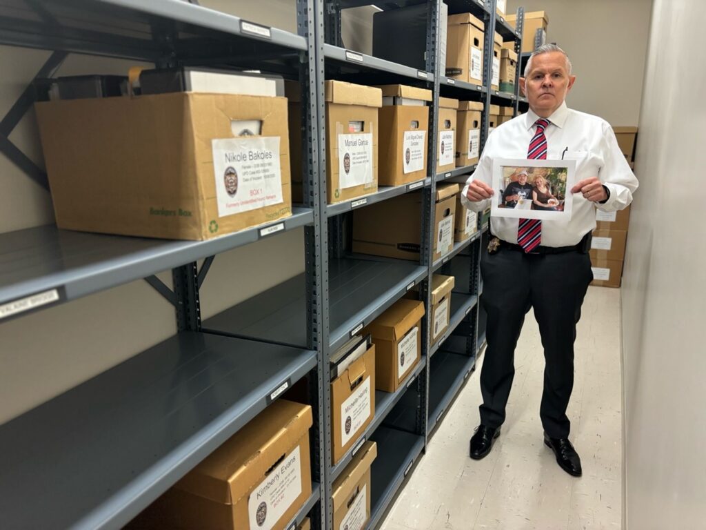 Detective Pender in their evidence room with a photo of Ralph and Alice.